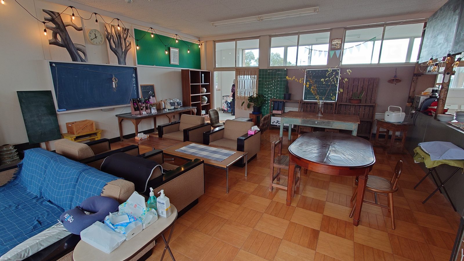 旧石出小学校の保健室をリノベーションした、明るい日替わりカフェの店内。大きな窓から光が差し込み、木のテーブルやソファが並ぶ。